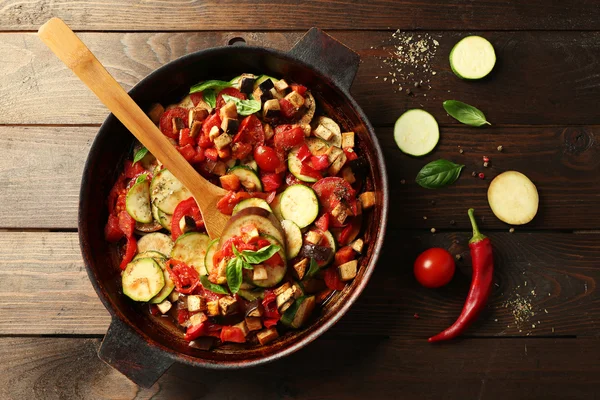 Lezzetli vejetaryen ratatouille, patlıcan yapılan squash, domates ve soğan siyah dökme demir, ahşap masa arka plan üzerinde tava — Stok fotoğraf