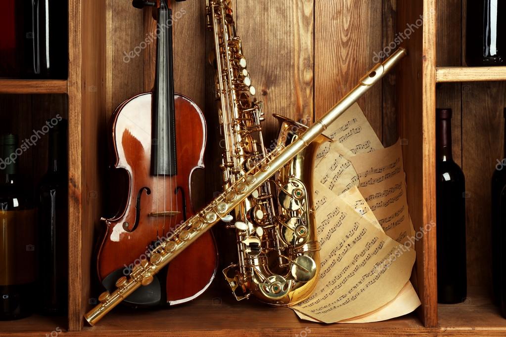 Musical instruments: saxophone, violin and flute with notes on wooden  background Stock Photo by ©belchonock 91285750