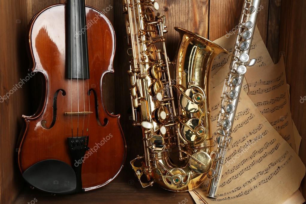 Musical instruments saxophone, violin and flute with notes on wooden