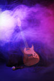 Velké reproduktory s elektrickou kytaru a mikrofon v hustém kouři pod fialovým světlem
