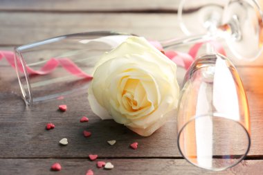 A bottle of wine, a glass, a white rose and a gift in the box, on wooden background