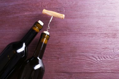 İki şişe şarap ve tirbuşon mor ahşap zemin üzerine