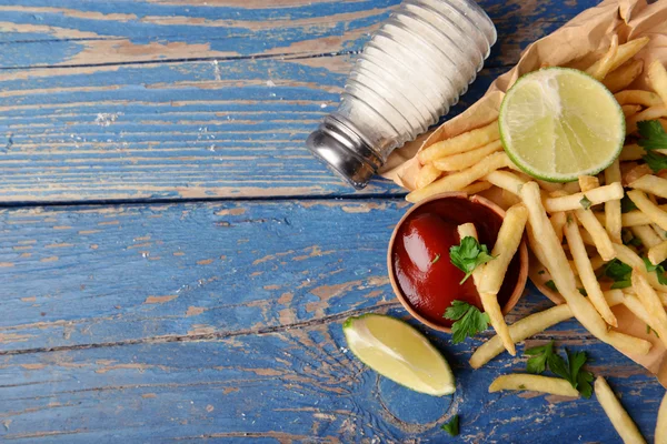 Papas fritas en papel artesanal sobre tabla de cortar —  Fotos de Stock