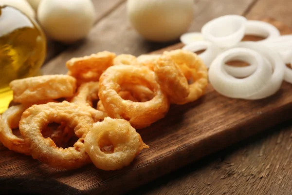 Anéis de batatas fritas com molho e cebola na tábua de corte — Fotografia de Stock