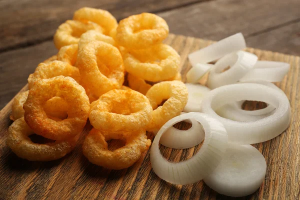 Anéis de batatas fritas com molho e cebola na tábua de corte — Fotografia de Stock