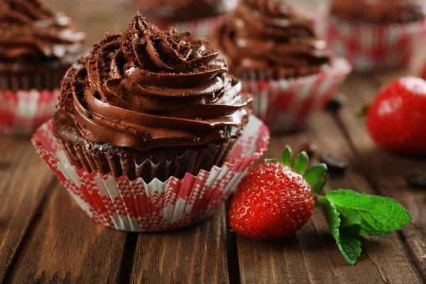 Chocolate cupcakes and strawberries on wooden background — Stock Photo, Image