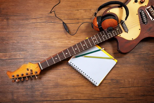 Elektrische gitaar en koptelefoon op houten achtergrond — Stockfoto