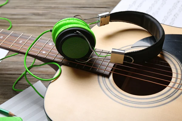 Klassische Gitarre und Kopfhörer mit Noten auf Holzgrund — Stockfoto