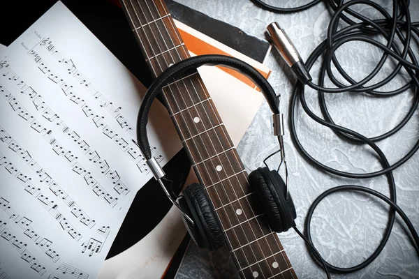 Electric guitar and headphones with music notes on grey background