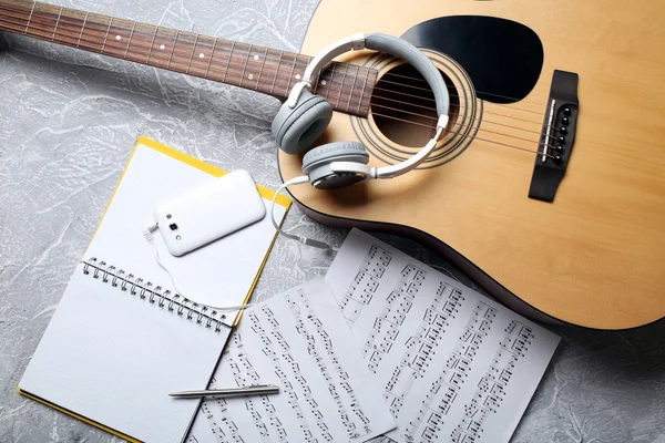 Chitarra classica e cuffie con telefono su sfondo grigio — Foto Stock