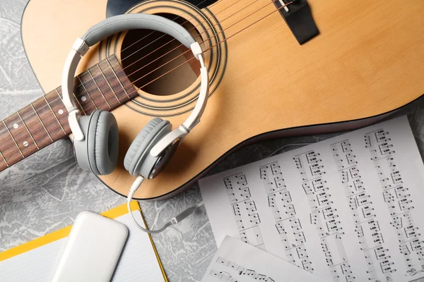 Guitarra clásica y auriculares con teléfono sobre fondo gris —  Fotos de Stock