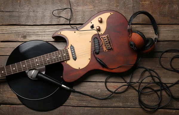Electric guitar and headphones with microphone and vinyl on wooden background — Stock Photo, Image