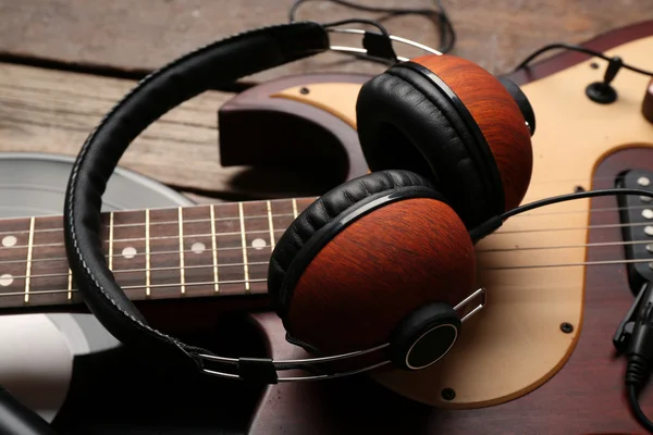 Electric guitar and headphones with vinyl on wooden background — Stock Photo, Image