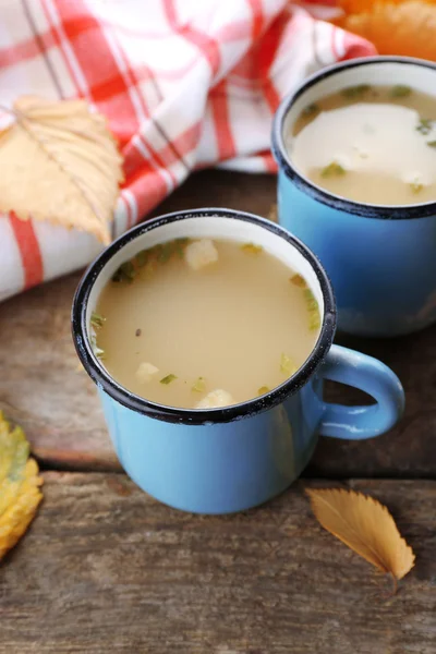 Zwei Tassen Suppe und Serviette auf hölzernem Hintergrund — Stockfoto