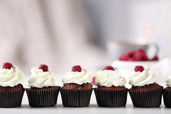 Belos cupcakes de chocolate com creme e framboesa na mesa — Fotografia de Stock