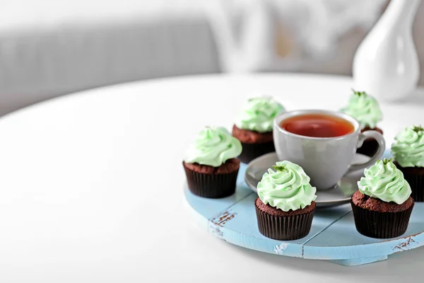 Belos cupcakes de chocolate e xícara de chá, na mesa — Fotografia de Stock