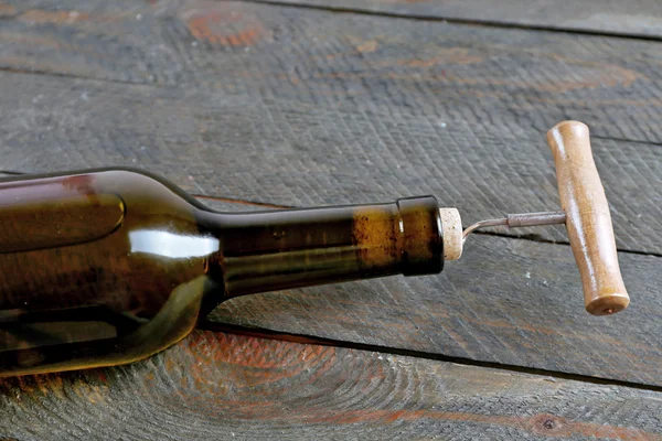 Bottle of wine with corkscrew on wooden background — Stock Photo, Image