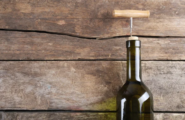 Butelka wina z korkociągiem na drewnianym tle — Zdjęcie stockowe
