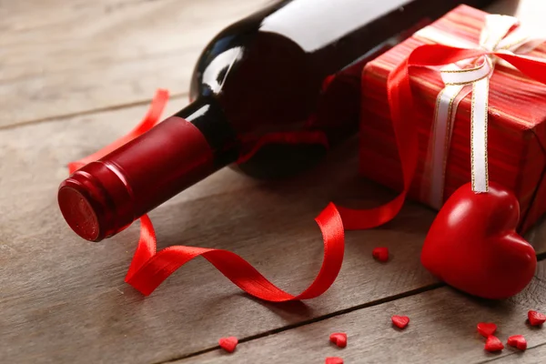 A bottle of wine and a gift in the box, on wooden background — Stock Photo, Image