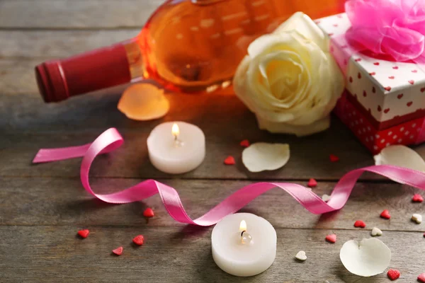 Une bouteille de vin, des bougies, une rose blanche et un cadeau dans la boîte, sur fond de bois — Photo