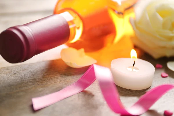 Eine Flasche Wein, eine Kerze und eine weiße Rose auf hölzernem Hintergrund — Stockfoto