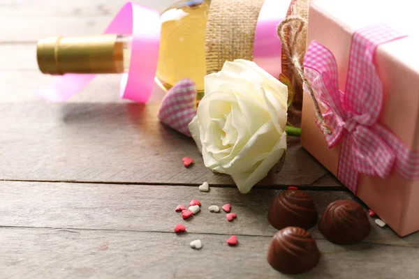 Setting of a bottle of wine, a gift in the box and other decoration, on wooden background — Stock Photo, Image