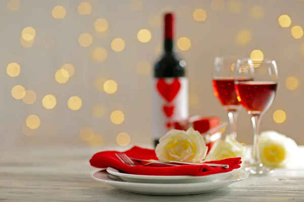 Instelling van glazen met wijn, fles en een geschenk in het vak op witte onscherpe achtergrond — Stockfoto