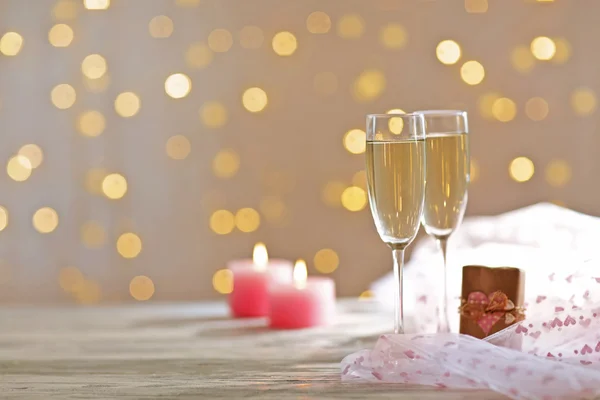 Copos de vinho, um presente na caixa e velas, sobre fundo borrado — Fotografia de Stock