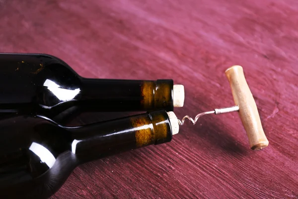İki şişe şarap ve tirbuşon mor ahşap zemin üzerine — Stok fotoğraf