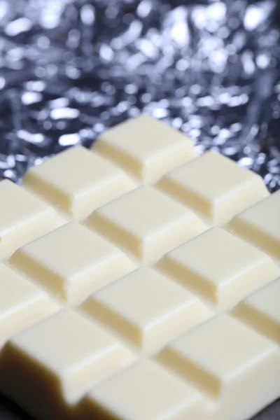 Witte chocoladereep in folie, close-up — Stockfoto