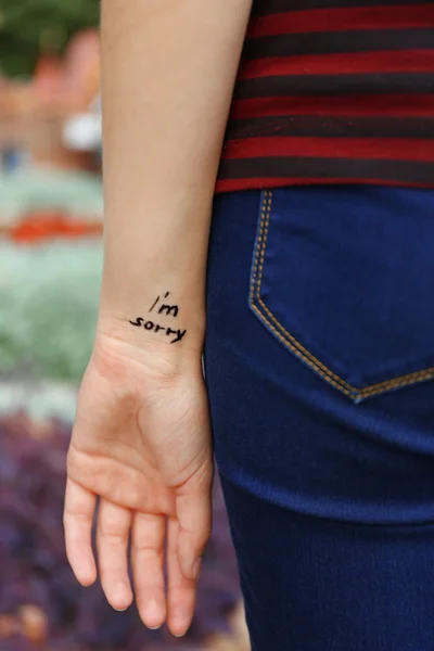 Main de jeune femme avec phrase tatouée — Photo