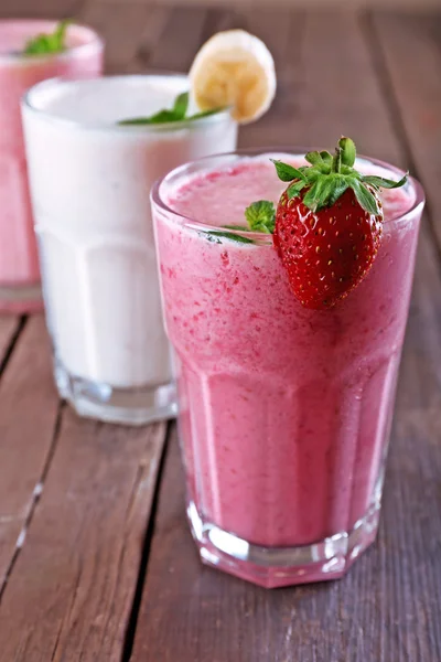 Vasos de batido frío fresco con frutas y bayas, sobre fondo de madera —  Fotos de Stock