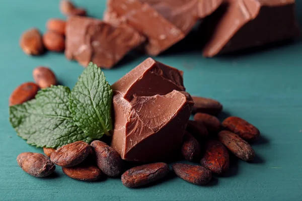 Tejes csokoládé darab és kakaó beans-színű fából készült háttér — Stock Fotó