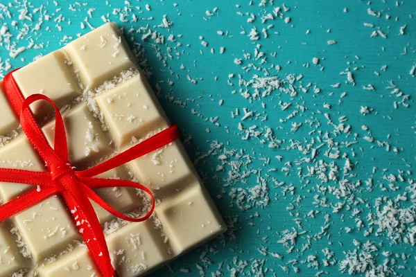 White chocolate bar with coconut shavings on color wooden background — Stock Photo, Image