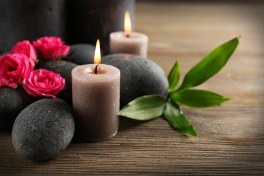Ahşap arka plan üzerinde gri mum gül ve çakıl yanıyor - kavramı relax