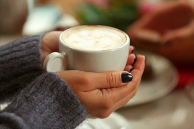 Kafede elinde kahve tutan bir kadın.