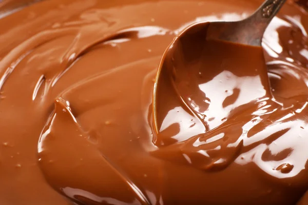 Background of melted milk chocolate and a spoon, close-up — Stock Photo, Image