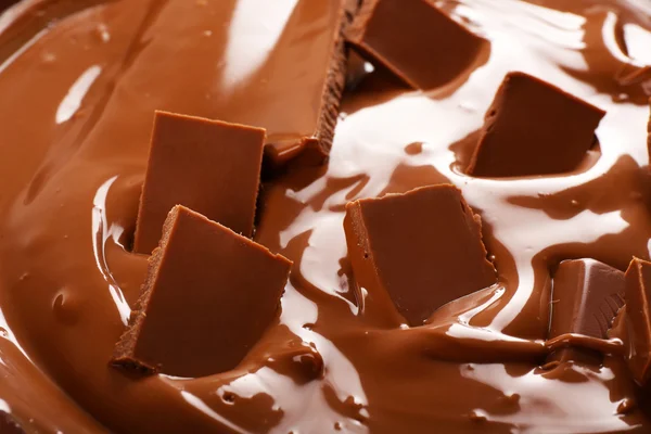 พื้นหลังของช็อคโกแลตนมละลายและชิ้นส่วนของบาร์, close-up — ภาพถ่ายสต็อก