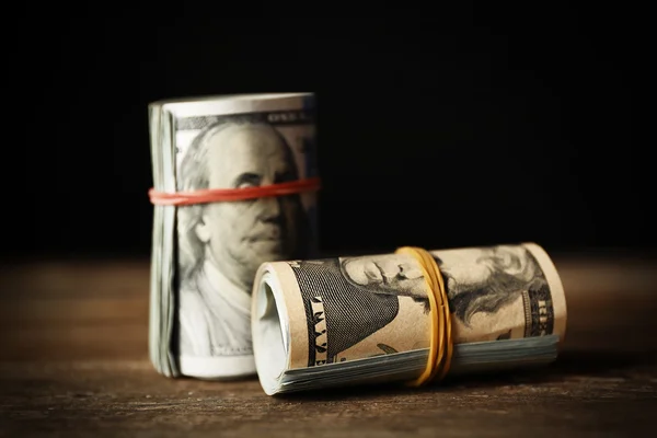 Доллары катятся на деревянном столе на темном фоне — стоковое фото
