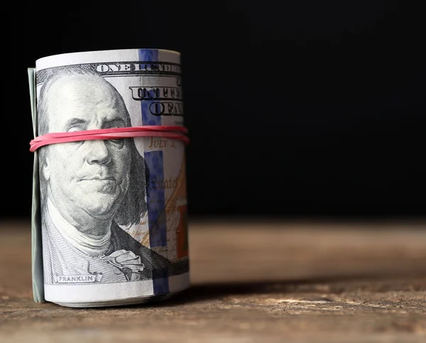 Доллары катятся на деревянном столе на темном фоне — стоковое фото