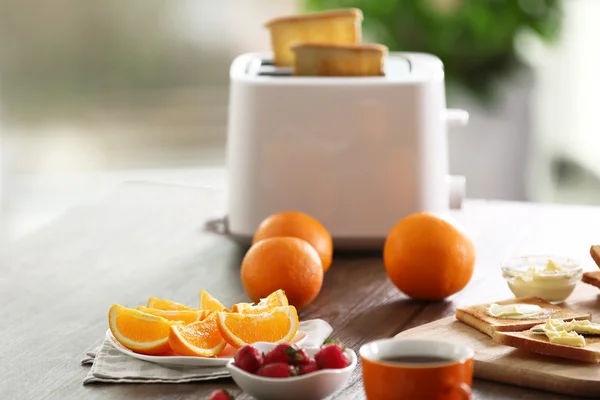 Mesa servida para el desayuno con tostadas, café y fruta, sobre fondo borroso — Foto de Stock