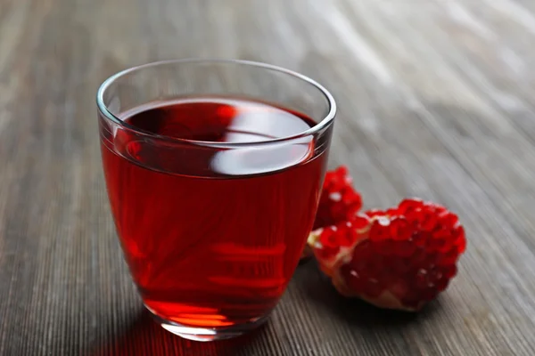 Kieliszek smaczny sok i owoce granatu, na tle drewniane — Zdjęcie stockowe
