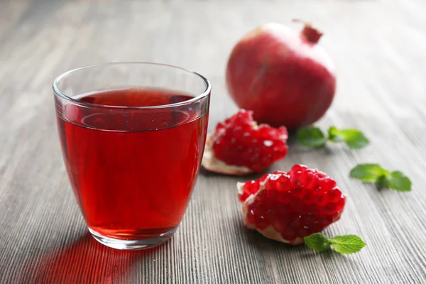 A glass of tasty juice and garnet fruit, on wooden background — Stock Photo, Image