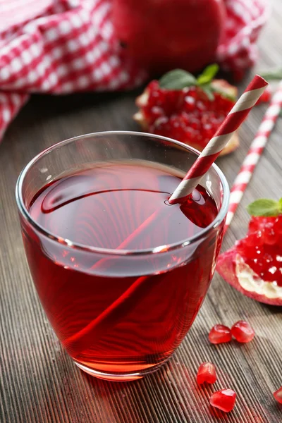 Un vaso de sabroso jugo y granate, sobre fondo de madera, primer plano — Foto de Stock