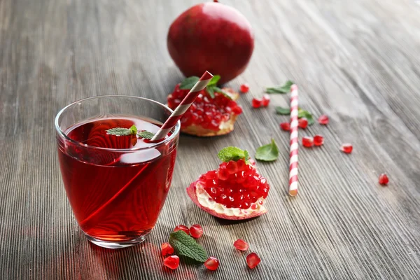 Ahşap arka plan üzerinde garnet meyve ve lezzetli suyu bir bardak — Stok fotoğraf