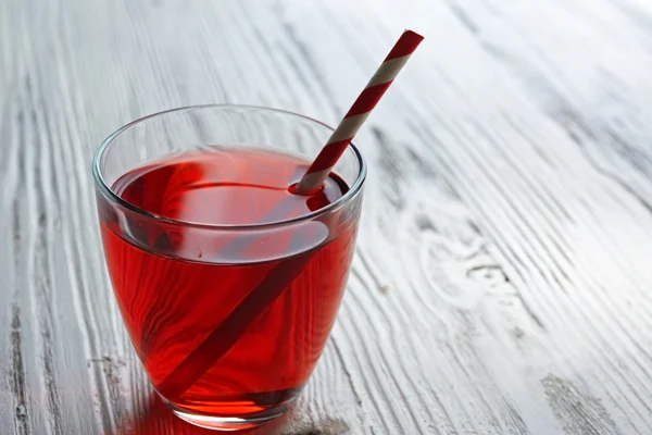 Un vaso de sabroso jugo de granate con una paja, sobre fondo de madera —  Fotos de Stock