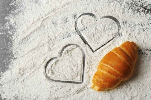 Herz aus Mehl und frischen Croissants auf Holzgrund — Stockfoto