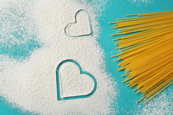 Coeur de farine et pâtes sur fond bleu — Photo