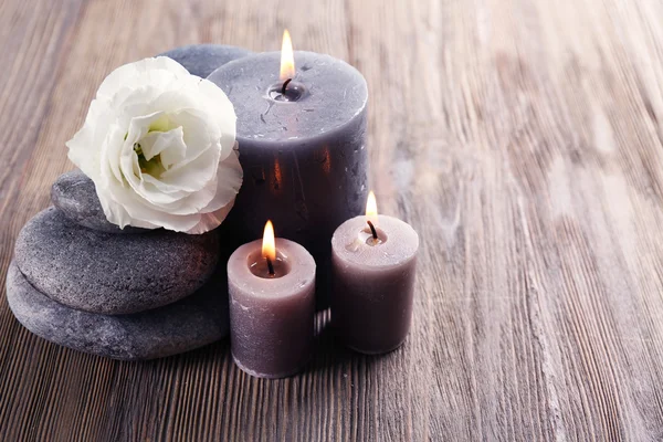 Свічка аромату з галькою та квіткою на дерев'яному фоні — стокове фото
