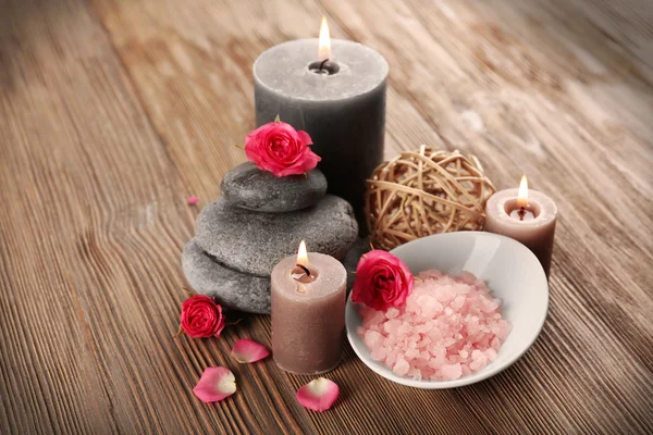 Relax set which include aroma candles, flowers, petals and pebbles on wooden background — Stock Photo, Image